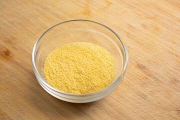 A view of a glass condiment cup of yellow cornmeal.