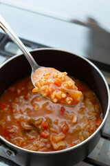 A view of a spoon scooping some tomato cabbage soup.