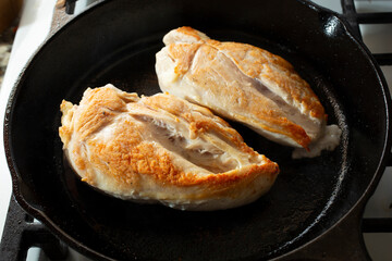 A view of chicken breasts frying in a skillet.