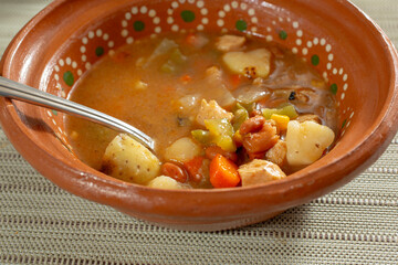 A view of a clay bowl of chicken chipotle soup.