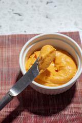 A view of a butter knife scooping some sweet potato dip from a bowl.
