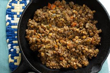 A top down view of a skillet of braised lentils.