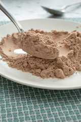 A view of a spoon scooping some protein powder from a plate.
