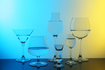 Different glasses with water on table, color tone effect