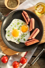 Tasty fried eggs with cut sausages served on wooden table, flat lay