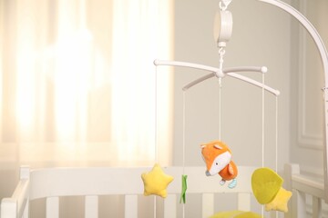 Crib with baby mobile in child's room, space for text
