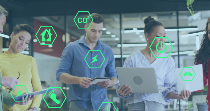 Image of ecology icons over diverse colleagues discussing work in office