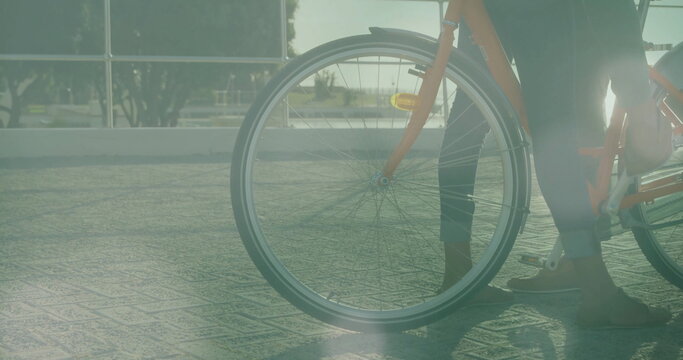 Image of light spots over biracial couple with bicycle at seaside