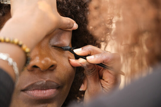 Makeup artist applying false eyelashes on african woman for wedding