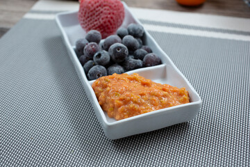 A view of an appetizer plate of guava puree and frozen berries.
