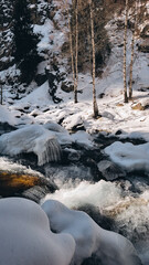 beautiful winter mountains scenery with hight rocks, cold river, birch trees and sunny weather