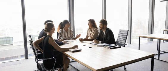 Five multiethnic shareholders gathered in conference room, discuss future strategy, joint projects details, partnership and collaboration, company recent financial results, revenue, or profit margins