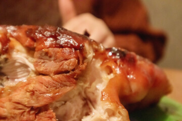 
oven-baked pork leg with crispy skin, served on a plate with vegetables and garnished with herbs.