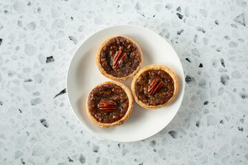 A top down view of a plate of bite-sized pecan pies.