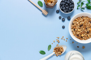 Bowls with oat granola and blueberries on light blue background with copy space. Food breakfast background top view