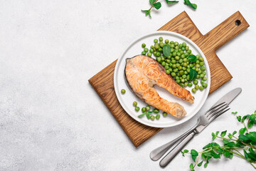 Roasted salmon steak with fresh green peas and mint on white plate. Healthy food light background...