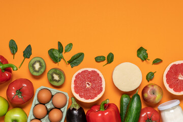 Fruits, vegetables, eggs, milk and cheese on orange copy space background. Healthy food delivery background. Grocery supermarket and clean eating concept