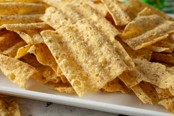 A closeup view of a pile of whole grain wavy chips, on a tray.