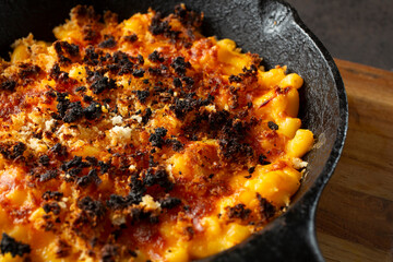 A closeup view of a rustic mac n cheese entree in a cast iron skillet.