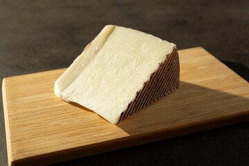A view of a block of Manchego cheese, on a wood board.