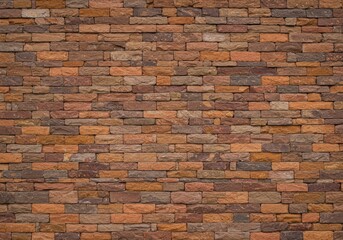 Obraz premium A photo of a brick wall with rough texture, featuring red, orange, and brown bricks in a running bond pattern, well-lit with natural light.