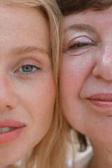 Close up portrait of a young red haired woman and her senior mother standing on the beach by the ocean during their vacation together. Daughter and mother on a trip. Mothers day.