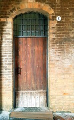 Old wooden door in the brick wall of an old house in Italy