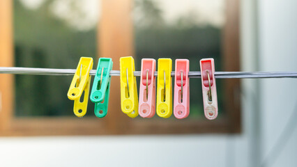 Colorful Plastic Clothespins on a Clothesline with Blurred Window Background