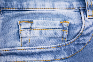 Blue jeans pocket close up. Details of jeans trousers with orange stitching