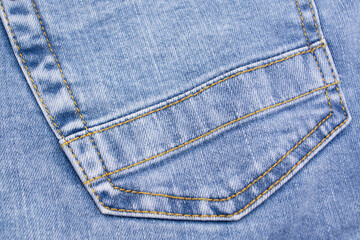 Blue jeans pocket close up. Details of jeans trousers with orange stitching