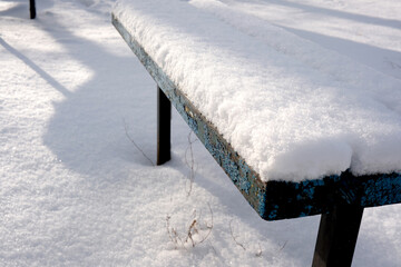 Snow blankets a weathered bench in a tranquil winter setting