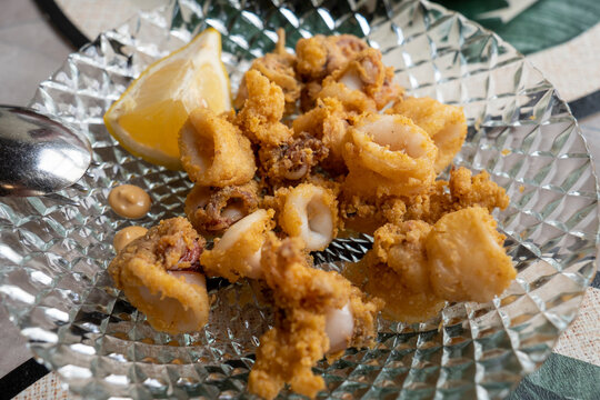 Spanish tapas: Plate of deep fried squids or Chipirones chopitos with lemon.