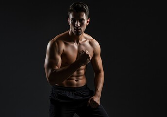 Fototapeta premium Powerful Athletic Man in Fitness Pose, Highlighting Muscular Body in Dark Studio Setting