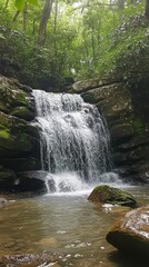 Fototapeta premium cascading waterfall, surrounded by lush greenery and moss-covered rocks, creates an enchanting natural scene. The water is crystal clear with soft ripples as it flows down the rocky surface