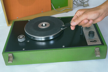Dj playing vinyl record on vintage portable record player