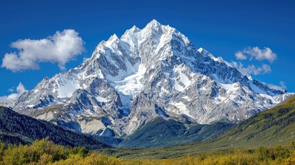 Obraz premium Snow-covered mountain peak rises into a clear blue sky above a green valley during a bright sunny day.