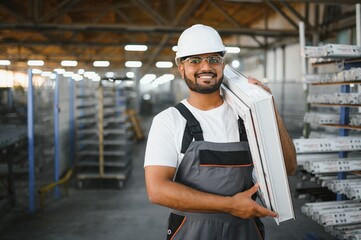 Operator of machine. Industrial worker indoors in factory. Young technician in white hard hat