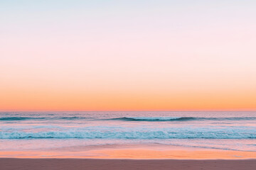 Obraz premium Tranquil beach sunset with soft pastel sky and gentle ocean waves touching the shore
