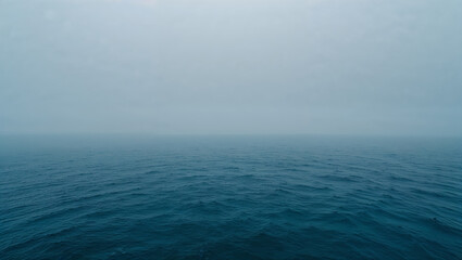 Fototapeta premium Deep blue sea merging with misty sky in a serene landscape