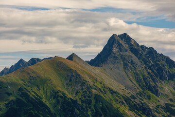 Fototapeta premium Mountain ridge in Tatras. View on tops Kasprowy Wierch and Swinica. Tatra National Park in Poland. Panorama of mountain landscape at summer in Tatras