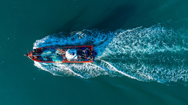 Fishing boat in the ocean for catching fish all a long night - at Thailand. Top view of Fishing Boat running verry fast on the sea to port - Powered by Adobe