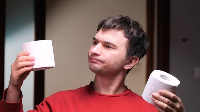 Man choosing between two toilet paper rolls in bathroom