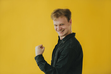Confident Man in Yellow Background Expressing Success and Positivity
