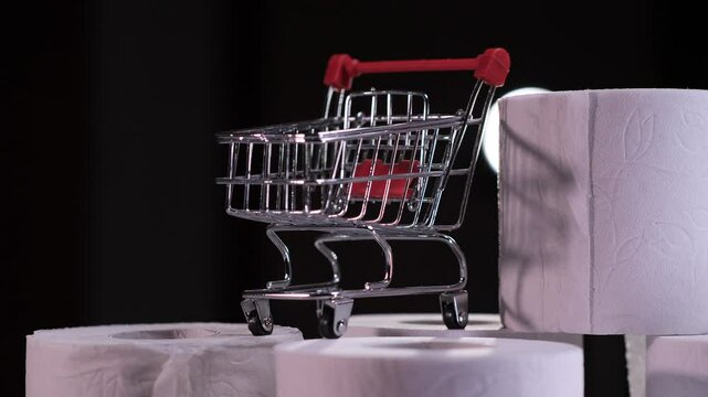 Shopping cart rolling on toilet paper rolls on black background