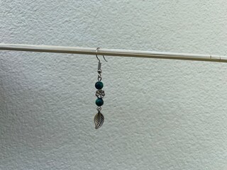 Silver earrings decorated with round green stones. Silverware carved in the shape of leaves and flowers.