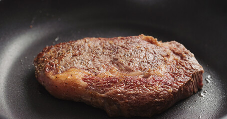 Closeup shot of ribeye steak frying on non stick pan
