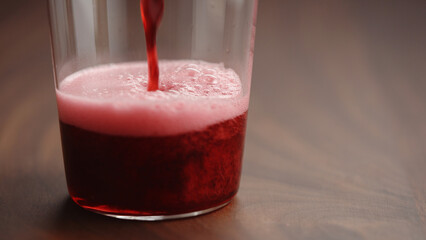 pour cherry drink in tumbler glass closeup