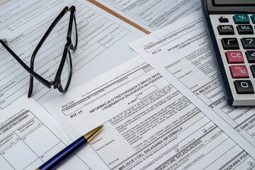 Calculating taxes in Poland, Pit different form with pen calculator glasses on desk