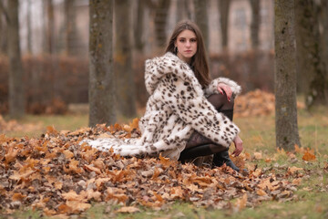 Portrait of a young beautiful dark-haired girl in a fur coat in nature.