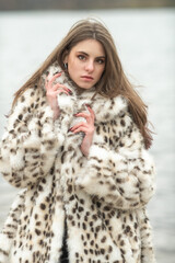 Portrait of a young beautiful dark-haired girl in a fur coat in nature.